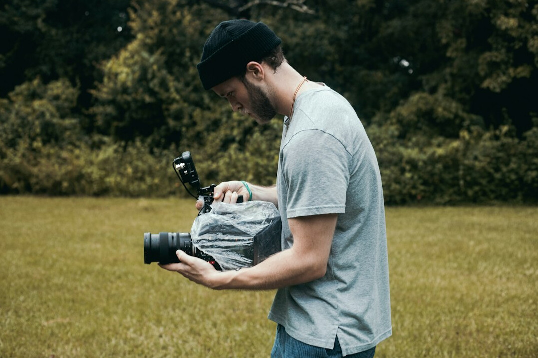 Man reportage videographer holding a compact camera and reflector